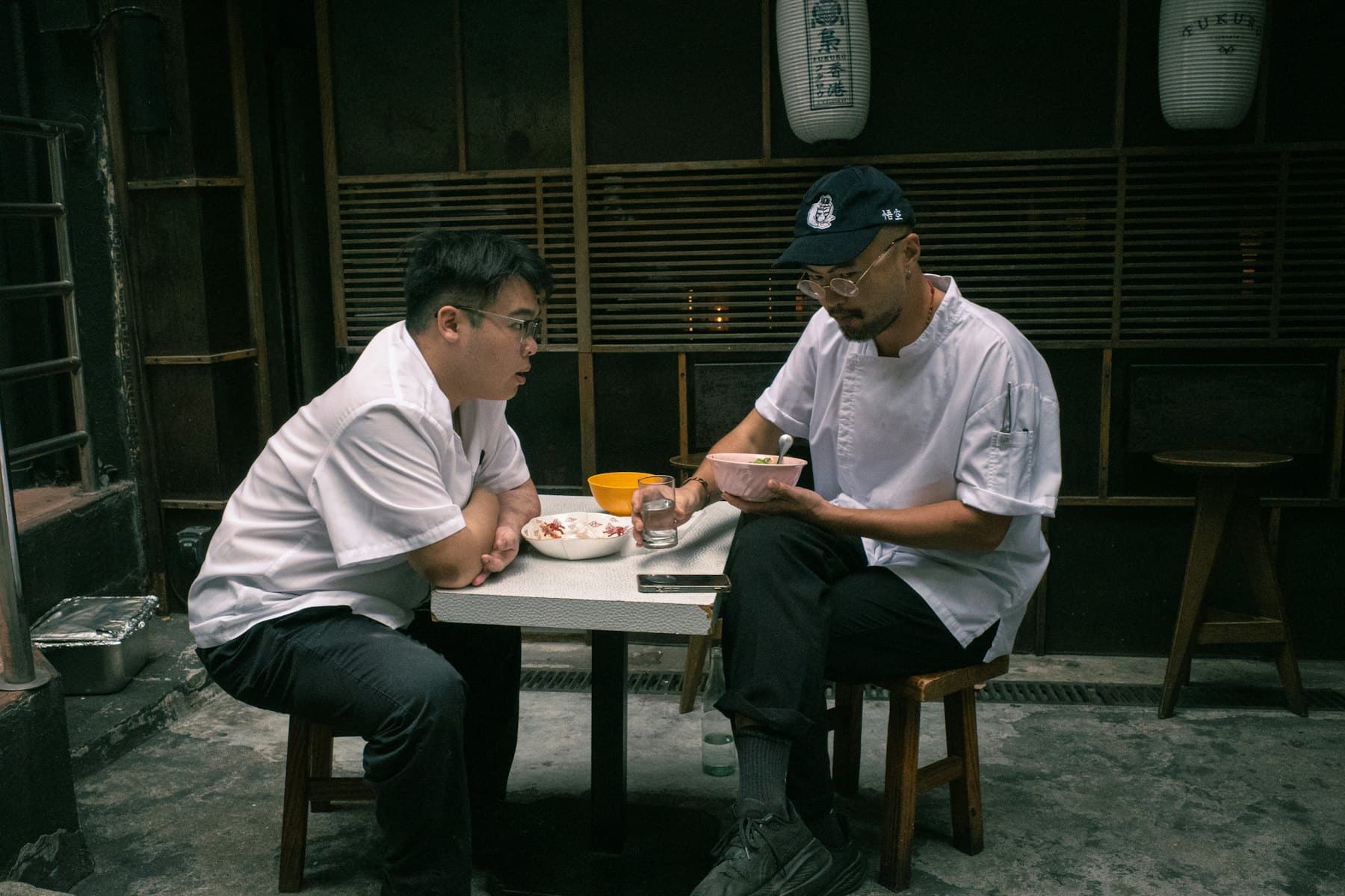 Dos cocineros conversando en una mesa mientras uno toma notas