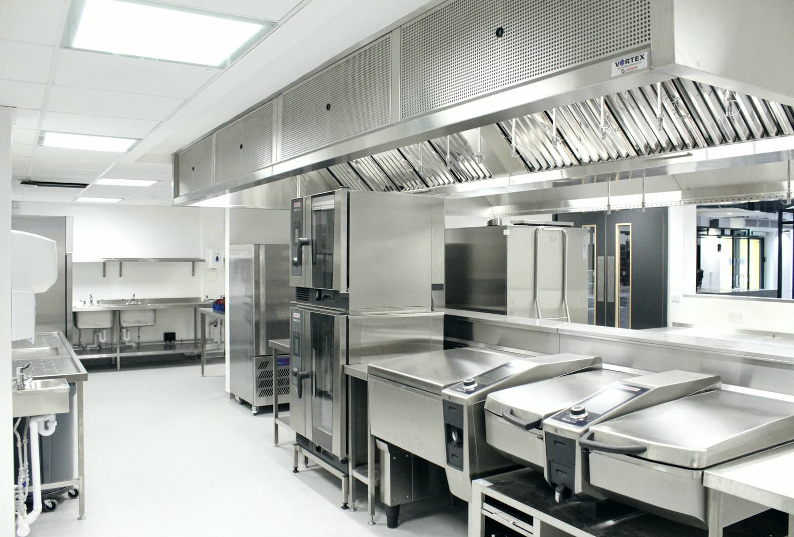 Cocina industrial de acero inoxidable con hornos y marmitas